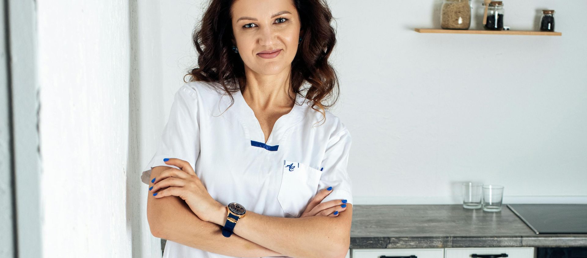 Professional woman standing confidently in a modern kitchen with arms crossed, exuding professionalism and elegance.